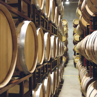 Beautiful rows of wooden barrels neatly stacked on racks, showcasing the inviting ambiance of a scenic winery storage room.