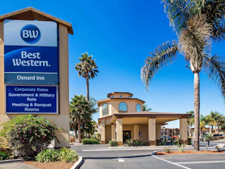 Welcoming entrance of Best Western Oxnard Inn with elegant palm trees, clear blue sky, and a prominent hotel sign.