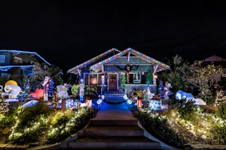 A charming house beautifully illuminated with vibrant Christmas lights and cheerful holiday figures, creating a magical nighttime scene.