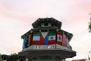 A vibrant pagoda adorned with international flags, including Australia, Germany, Philippines, and the United States, welcomes visitors.