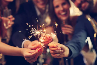 Joyful group celebrating with sparklers, surrounded by glowing festive lights, capturing a vibrant, welcoming atmosphere.