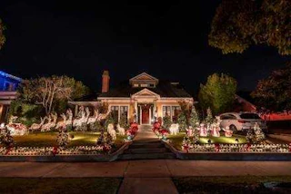 A beautifully decorated house shines at night with sparkling Christmas lights, cheerful reindeer figures, and festive lawn ornaments.